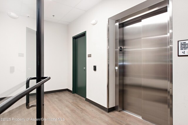 253 Wulfsohn Rd Unit 226, Glenwood Springs, CO 81601 - corridor with elevator, light wood-style flooring, a paneled ceiling, and baseboards