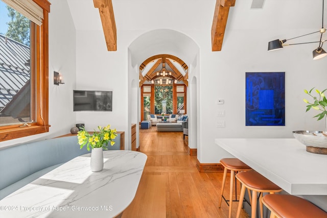 dining space with beam ceiling and light hardwood / wood-style flooring