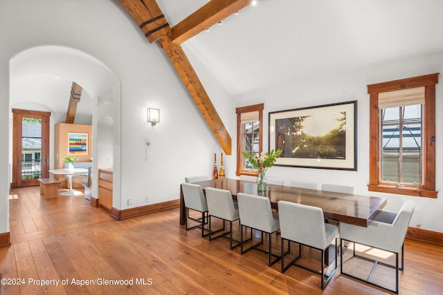 dining space with light hardwood / wood-style flooring and lofted ceiling with beams