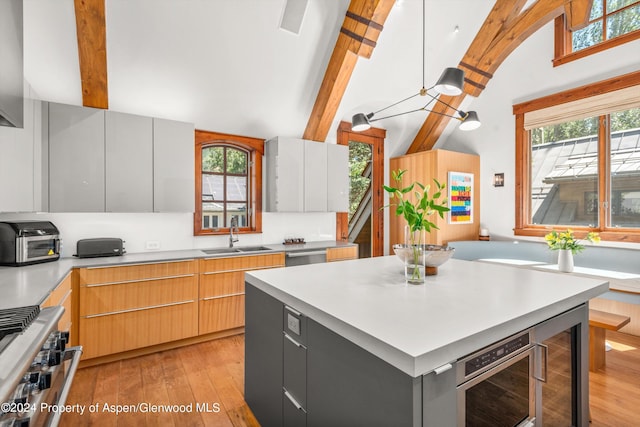 kitchen featuring stainless steel appliances, a center island, wine cooler, light hardwood / wood-style flooring, and sink