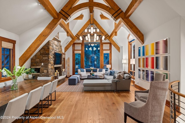 living room featuring a fireplace, a chandelier, light wood-type flooring, high vaulted ceiling, and beam ceiling