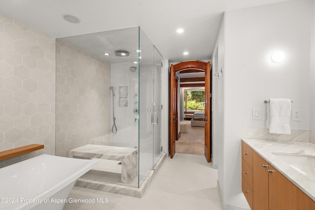 bathroom with independent shower and bath, tile walls, tile patterned floors, and vanity