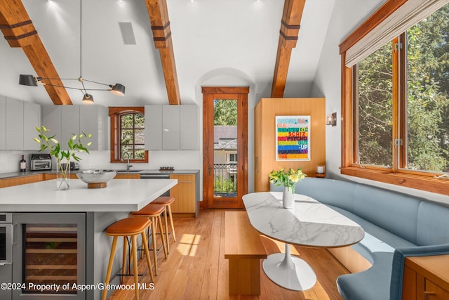 kitchen with beverage cooler, white cabinetry, sink, light wood-type flooring, and a breakfast bar area