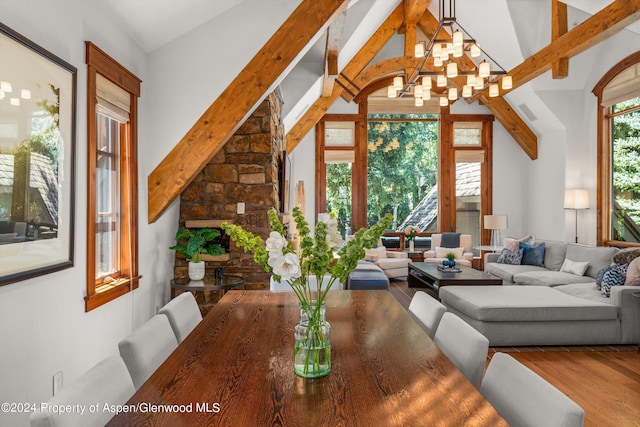 dining room featuring wood-type flooring, a wealth of natural light, beam ceiling, and a notable chandelier