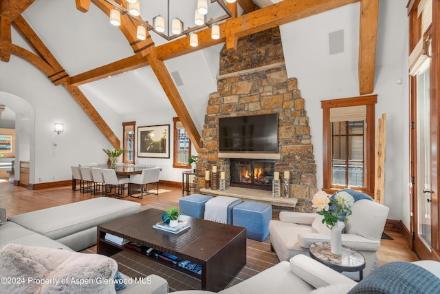 living room with a wealth of natural light, beam ceiling, a fireplace, and high vaulted ceiling