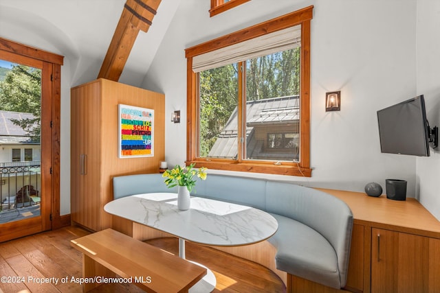 dining space featuring breakfast area, lofted ceiling with beams, and light wood-type flooring