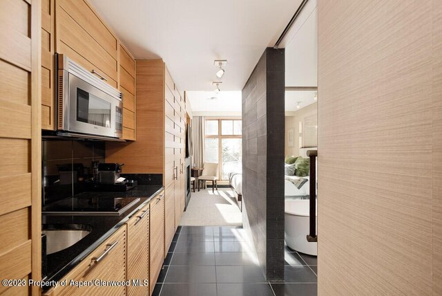 kitchen with light brown cabinets and dark tile patterned flooring