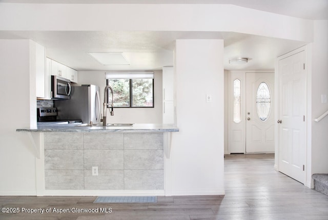 681 S 2nd St Unit A, Carbondale, CO 81623 - kitchen featuring wood finished floors, appliances with stainless steel finishes, baseboards, and white cabinetry