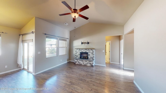 unfurnished living room featuring hardwood / wood-style flooring, vaulted ceiling, ceiling fan, and a stone fireplace