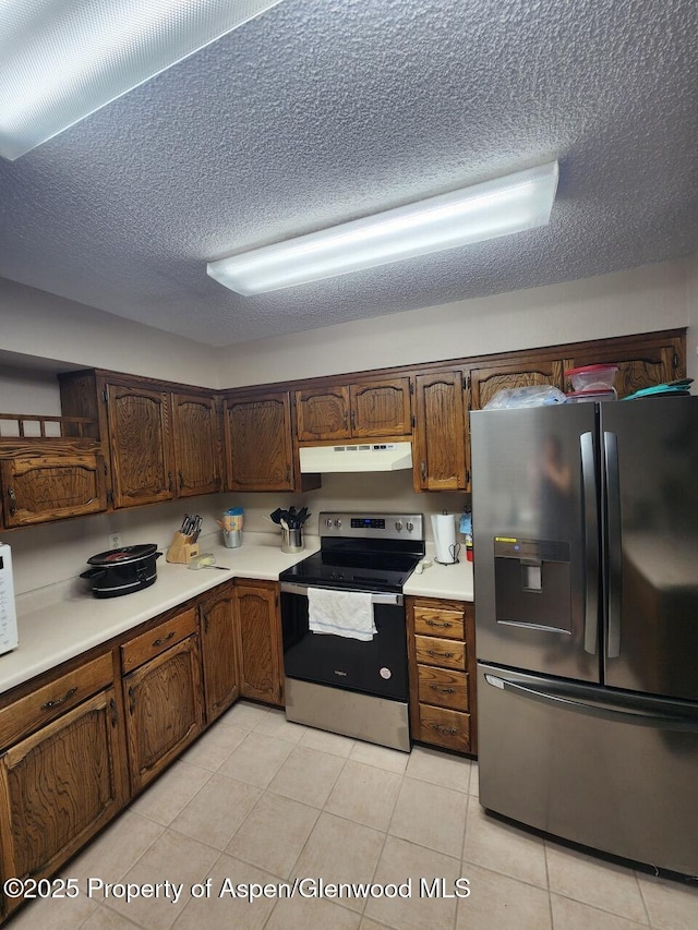 3057 Wellington Ave, Grand Junction, CO 81504 - kitchen with stainless steel appliances, under cabinet range hood, a textured ceiling, light countertops, and light tile patterned flooring