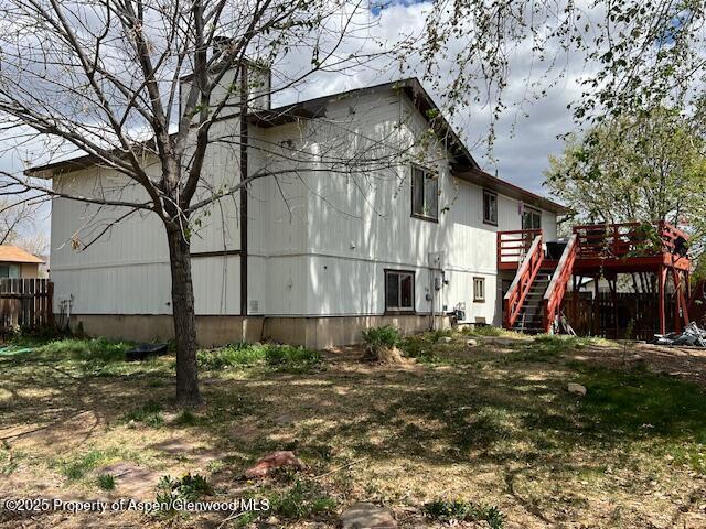 back of property with a wooden deck, stairway, and fence