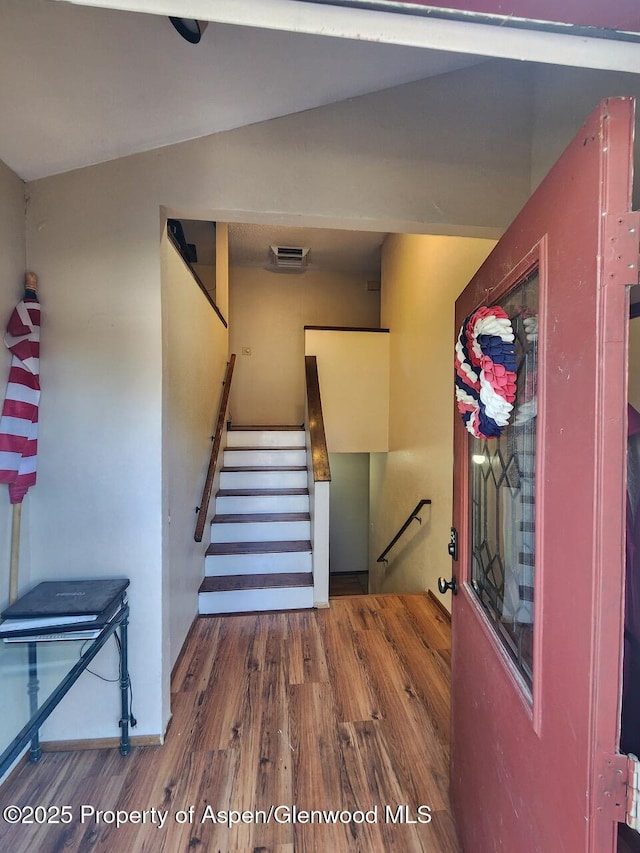 stairs with wood finished floors and visible vents