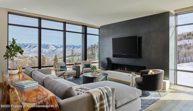 living room with expansive windows, light hardwood / wood-style flooring, and a tiled fireplace