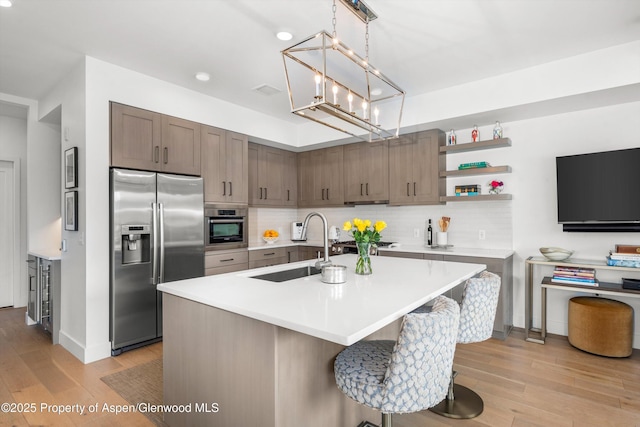 kitchen featuring an inviting chandelier, a center island with sink, sink, appliances with stainless steel finishes, and a breakfast bar area