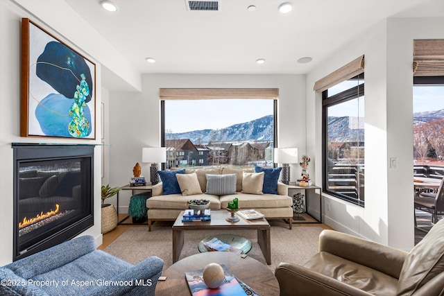 living room featuring a glass covered fireplace, a mountain view, visible vents, and wood finished floors