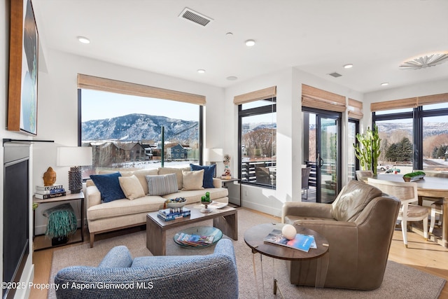 living area with recessed lighting, visible vents, light wood-style flooring, and a mountain view