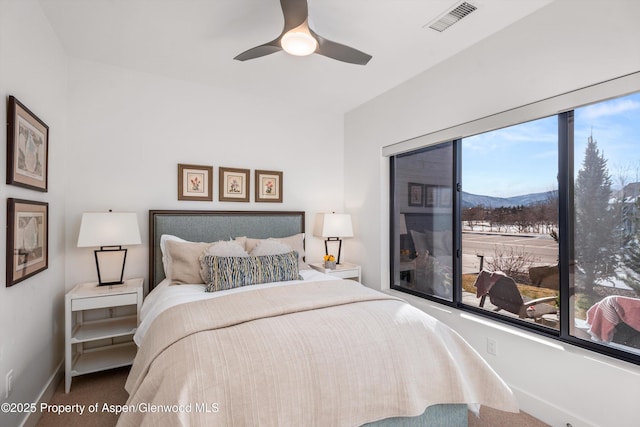 bedroom with a mountain view, carpet, multiple windows, and ceiling fan