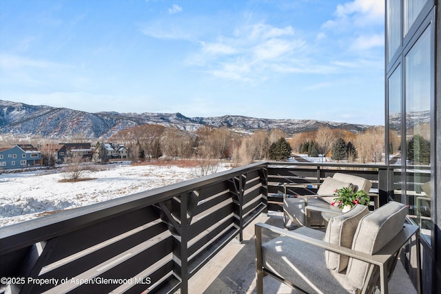 snow covered back of property featuring a mountain view