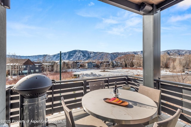 snow covered patio with a mountain view, a balcony, and grilling area