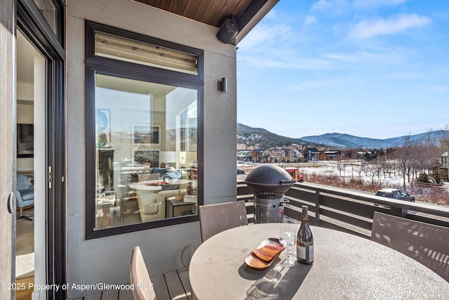 snow covered patio with a mountain view and a balcony