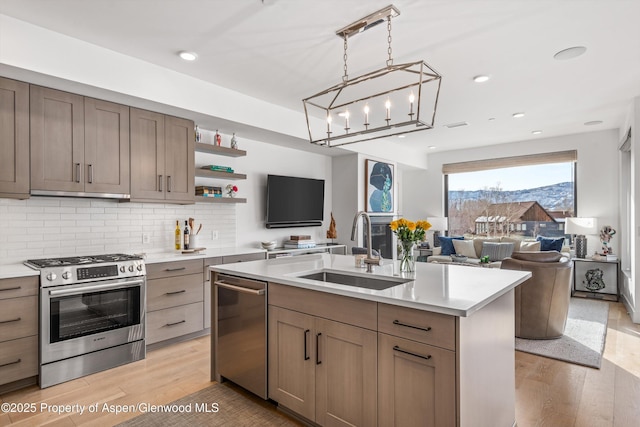 kitchen with sink, light hardwood / wood-style floors, a center island with sink, and appliances with stainless steel finishes