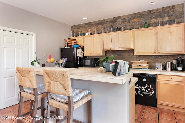 1199 Vitos Way, Carbondale, CO 81623 - kitchen featuring black appliances, light brown cabinetry, a kitchen breakfast bar, tile countertops, and light tile patterned flooring