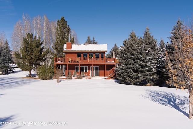 snow covered back of property featuring a deck