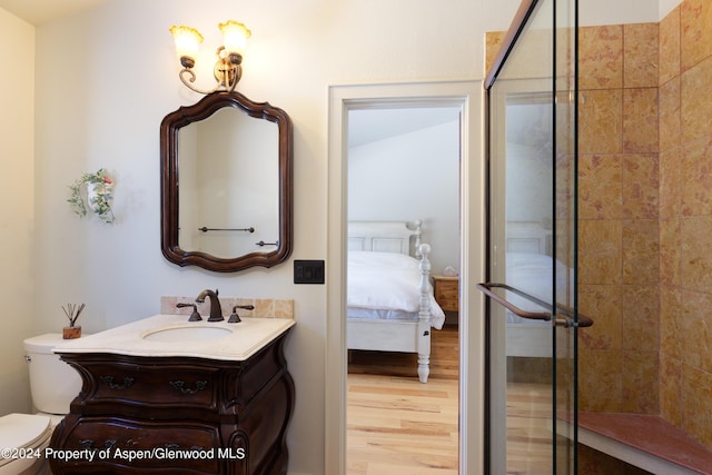 bathroom featuring tiled shower, hardwood / wood-style floors, vanity, and toilet