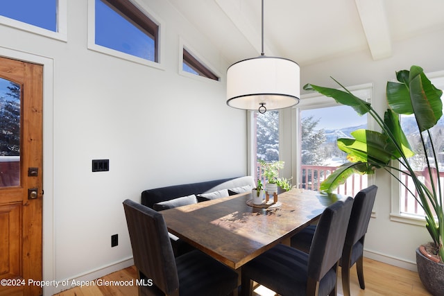 dining space with lofted ceiling with beams and light hardwood / wood-style flooring