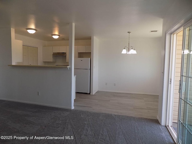 33 Angelica Cir, Parachute, CO 81635 - kitchen featuring freestanding refrigerator, under cabinet range hood, a chandelier, white cabinetry, and carpet flooring