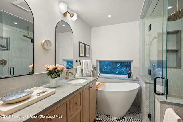 full bathroom with double vanity, a stall shower, a freestanding tub, and a sink