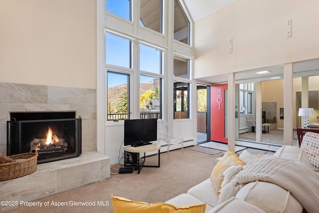 800 S Mill St Unit 301C, Aspen, CO 81611 - living room with a high ceiling, a tiled fireplace, carpet floors, and a baseboard radiator