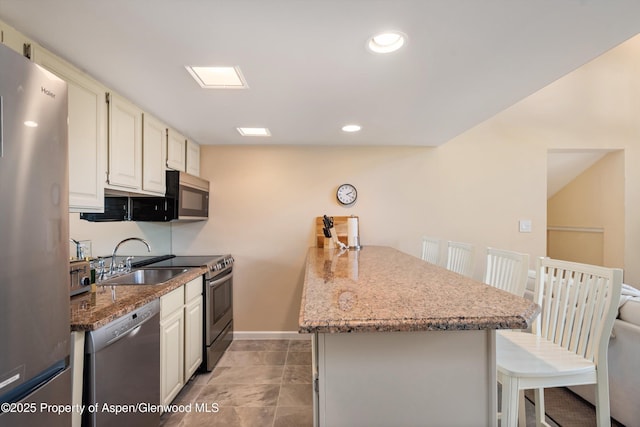 800 S Mill St Unit 301C, Aspen, CO 81611 - kitchen featuring stainless steel appliances, a kitchen breakfast bar, a peninsula, light stone countertops, and recessed lighting