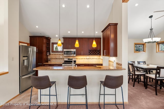 534/536 Spruce St, Aspen, CO 81611 - kitchen featuring stainless steel appliances, a peninsula, tasteful backsplash, a kitchen bar, and light stone countertops