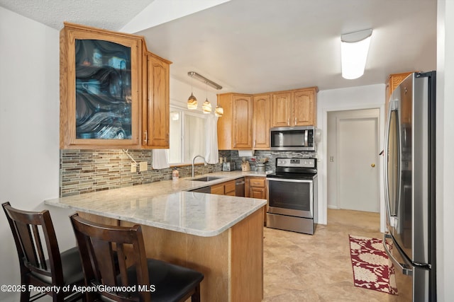 534/536 Spruce St, Aspen, CO 81611 - kitchen featuring appliances with stainless steel finishes, a peninsula, tasteful backsplash, a kitchen bar, and glass insert cabinets