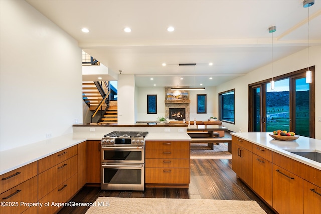 103 Ranch Ln, Glenwood Springs, CO 81601 - kitchen with range with two ovens, dark wood finished floors, light countertops, a fireplace, and a peninsula