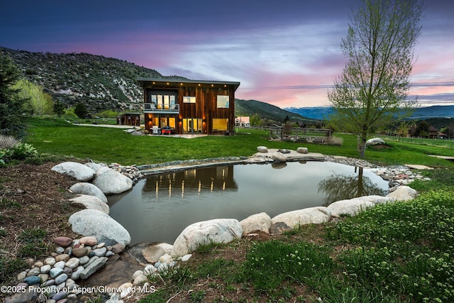103 Ranch Ln, Glenwood Springs, CO 81601 - back of property at dusk with a yard, a mountain view, and a garden pond
