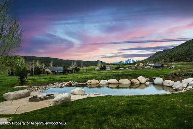 103 Ranch Ln, Glenwood Springs, CO 81601 - pool at dusk featuring a mountain view, a yard, and a fire pit