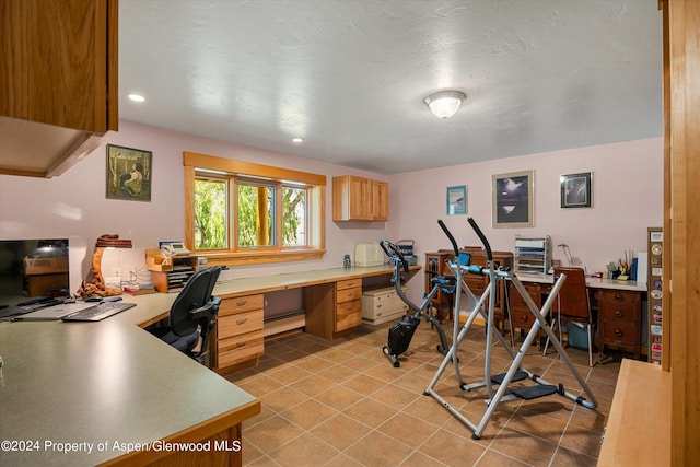 tiled home office featuring a textured ceiling, built in desk, and a baseboard radiator