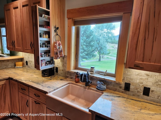 kitchen featuring decorative backsplash, light stone countertops, and sink