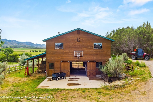 rear view of property with a mountain view, a rural view, and an outdoor structure