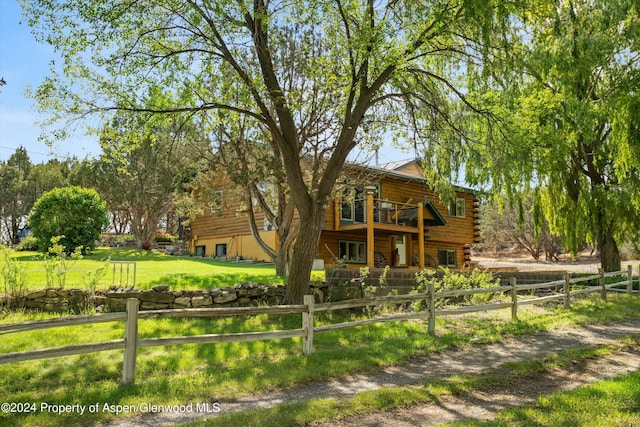 back of property featuring a lawn and a balcony