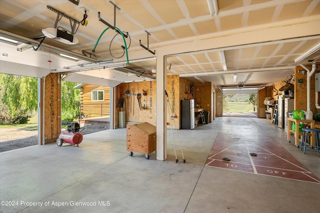 garage with stainless steel refrigerator and a garage door opener