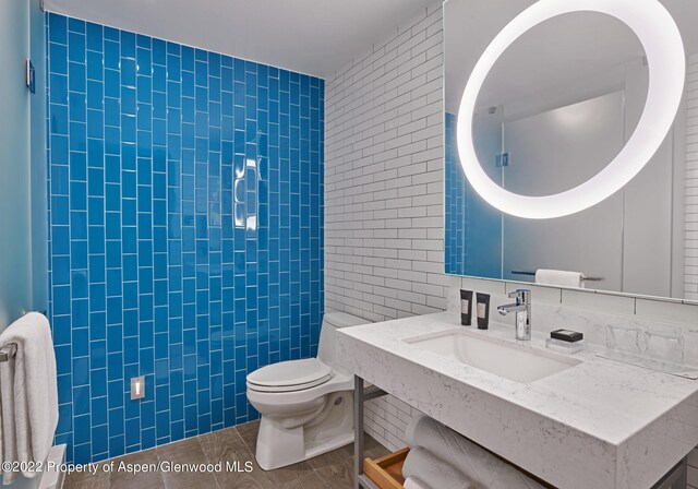 bathroom with tile patterned flooring, toilet, tile walls, and sink