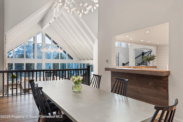 dining space with hardwood / wood-style flooring, high vaulted ceiling, and a chandelier