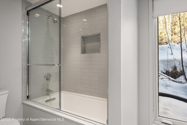 bathroom with combined bath / shower with glass door and toilet