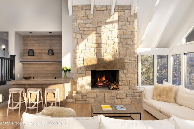 living room featuring wood-type flooring, a fireplace, high vaulted ceiling, and beamed ceiling