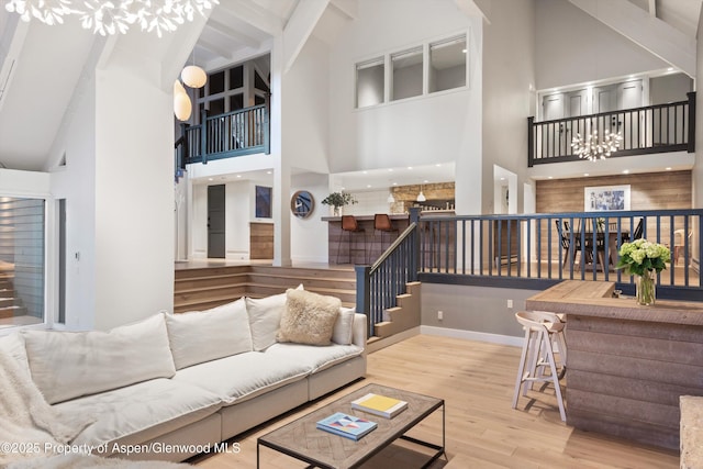 living room featuring high vaulted ceiling, hardwood / wood-style flooring, beamed ceiling, and a chandelier