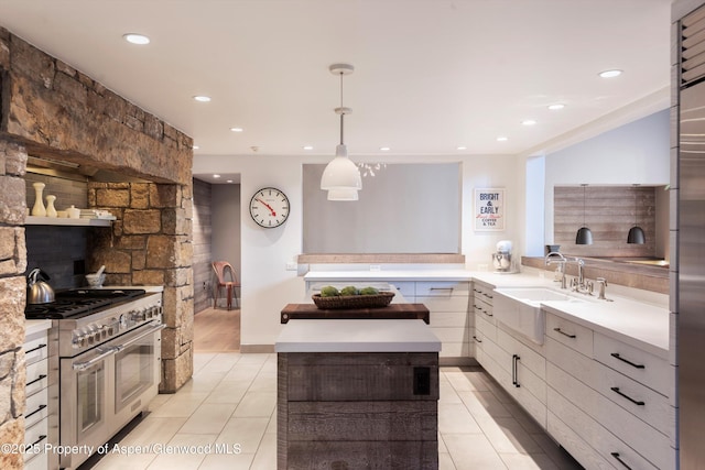 kitchen with light tile patterned floors, sink, range with two ovens, and pendant lighting