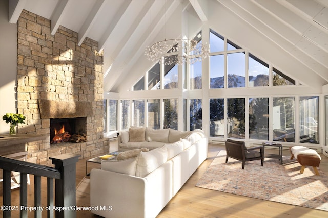 living room featuring a fireplace, light hardwood / wood-style floors, beam ceiling, a mountain view, and high vaulted ceiling